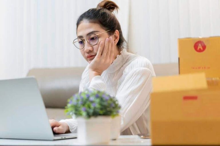 woman looking at laptop with product boxes next to her